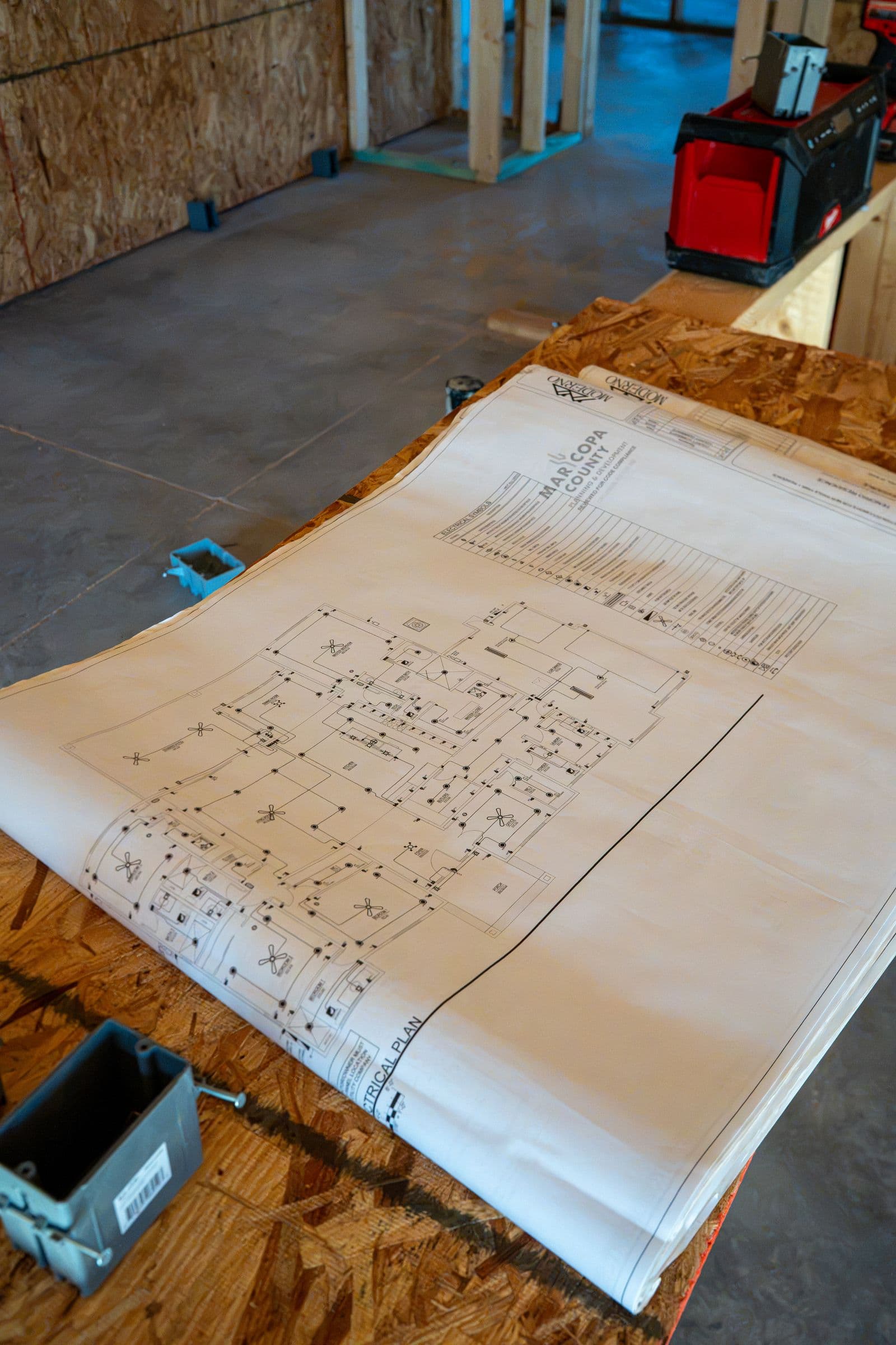 A blueprint on plywood with a new electrical box beside it