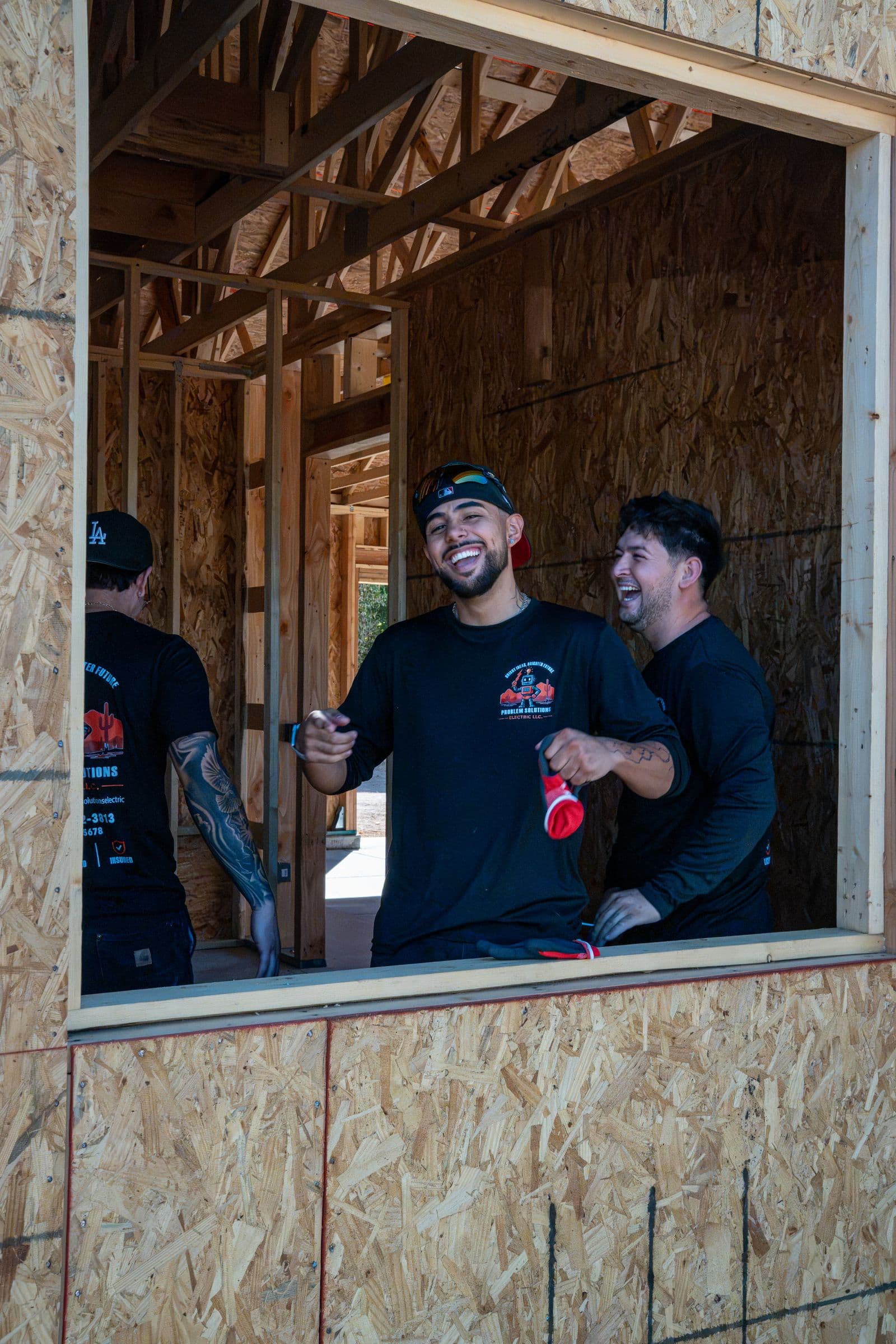 Three of the crew laughing inside a window opening on a new home