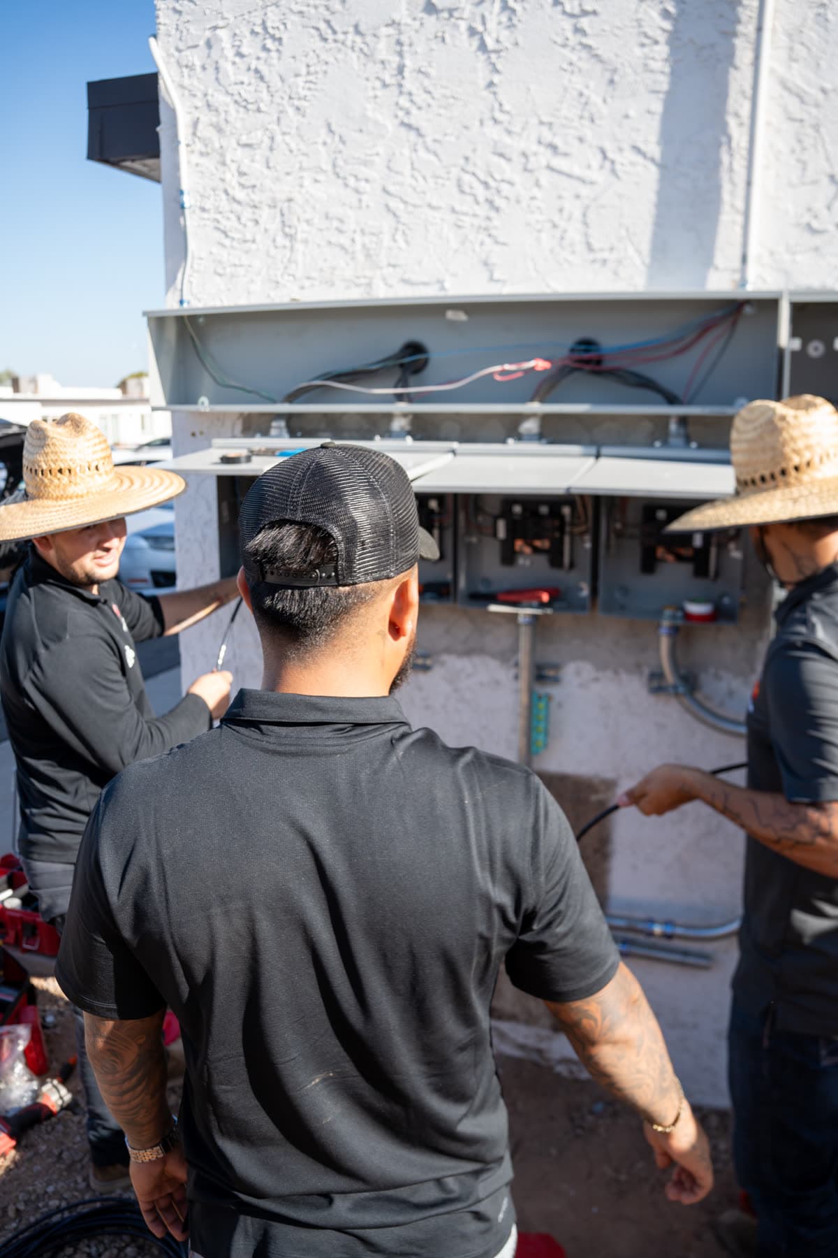 A technician talking the work through with two men at an open panel
