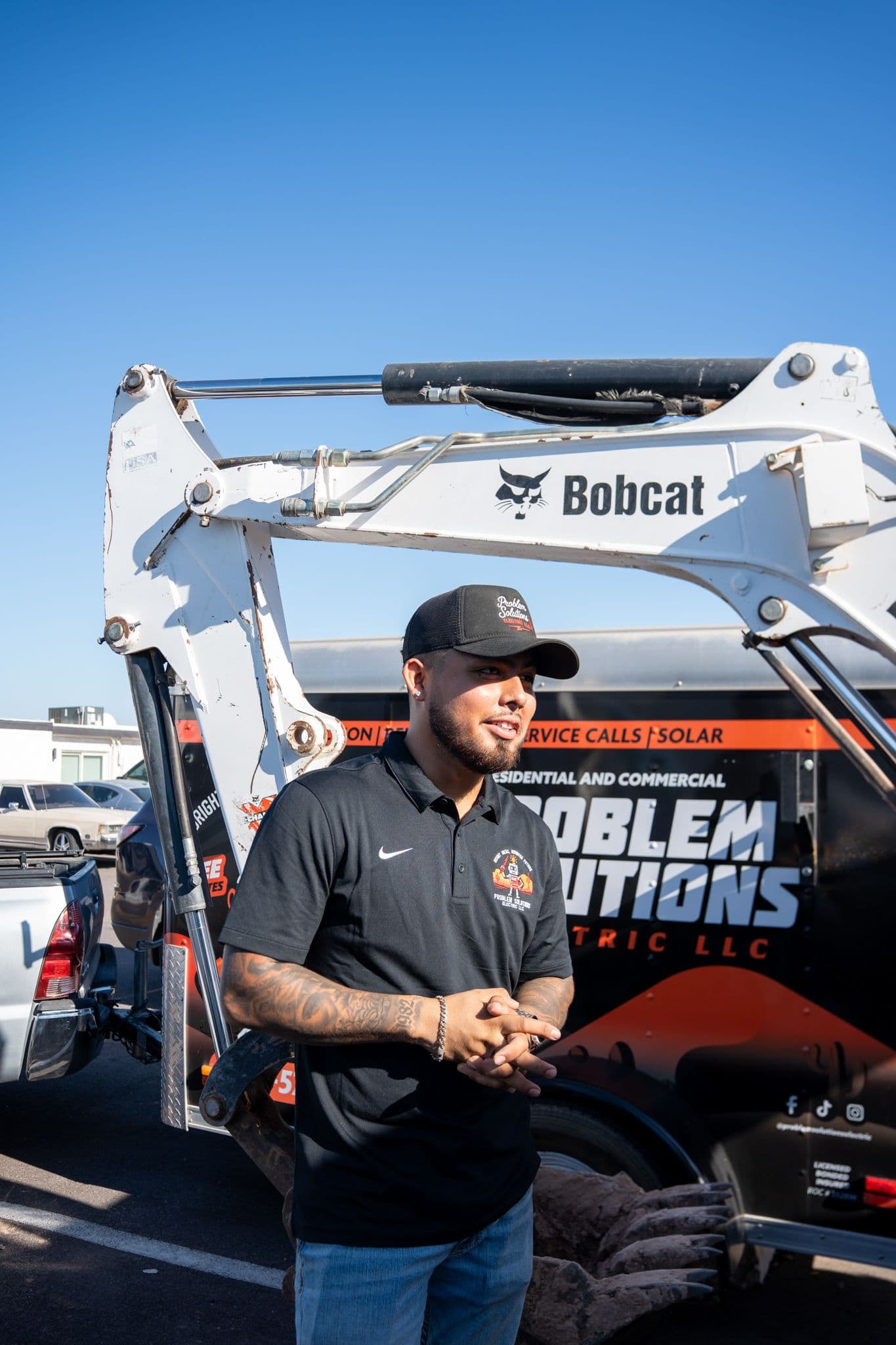 A technician in a company shirt talking beside the branded trailer