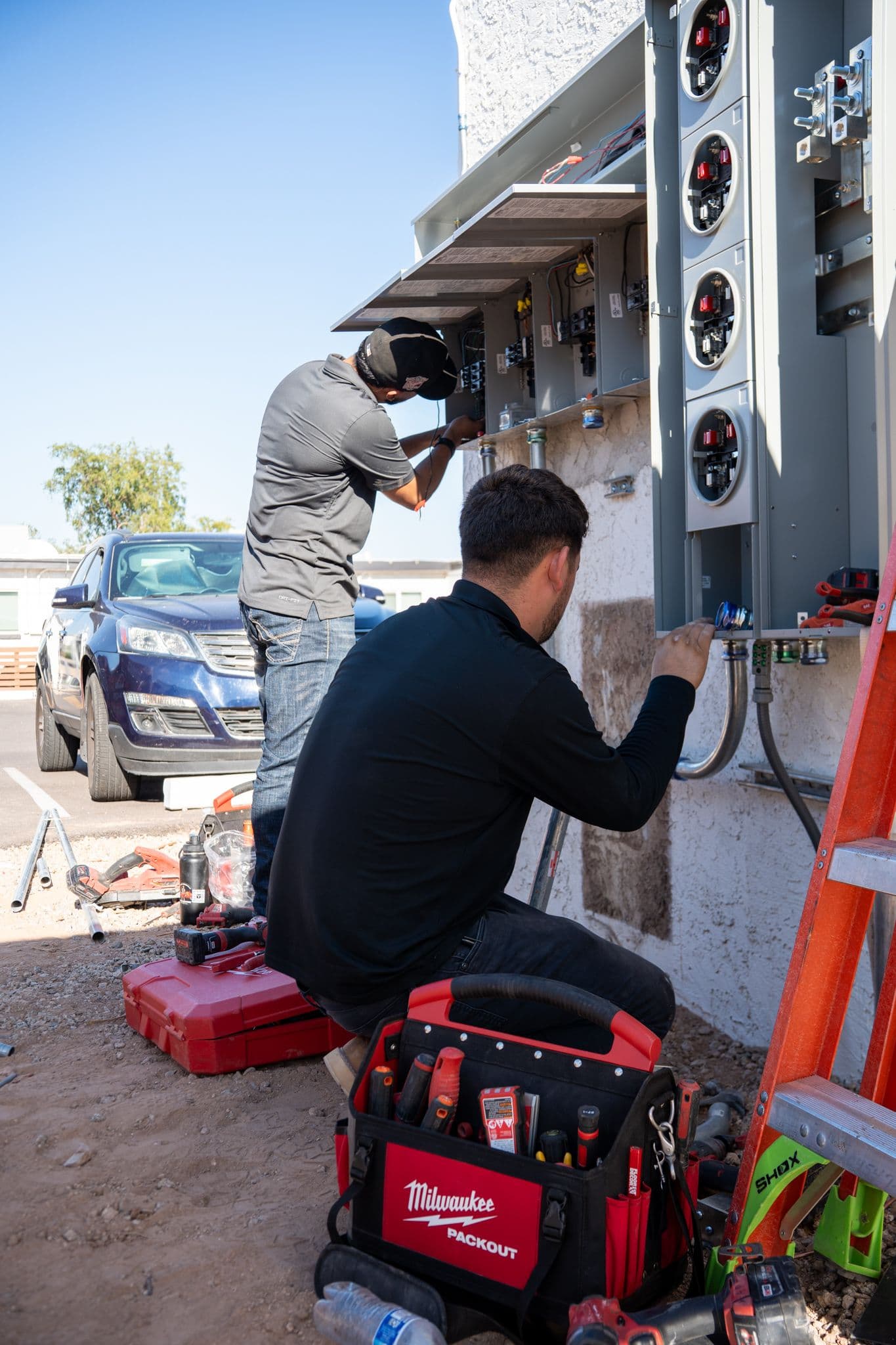 Two technicians wiring a new meter stack and panels